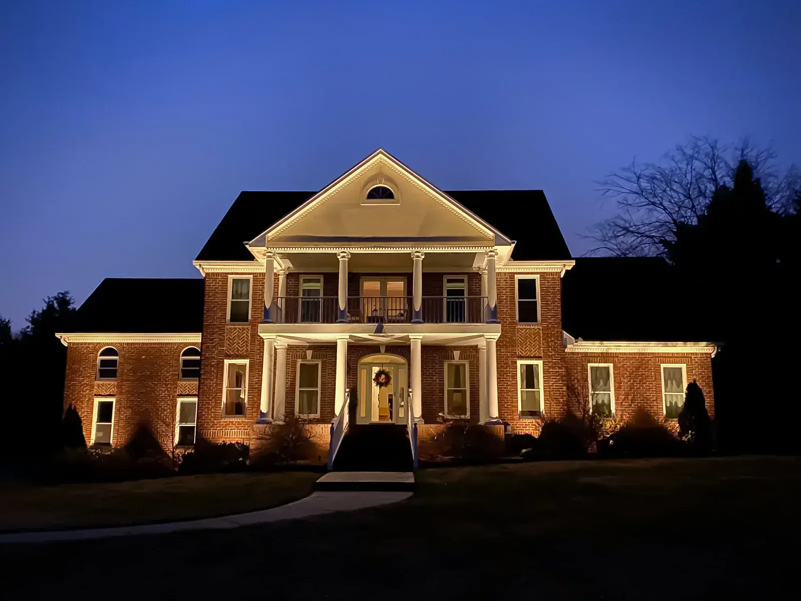Two-story colonial with column up-lighting