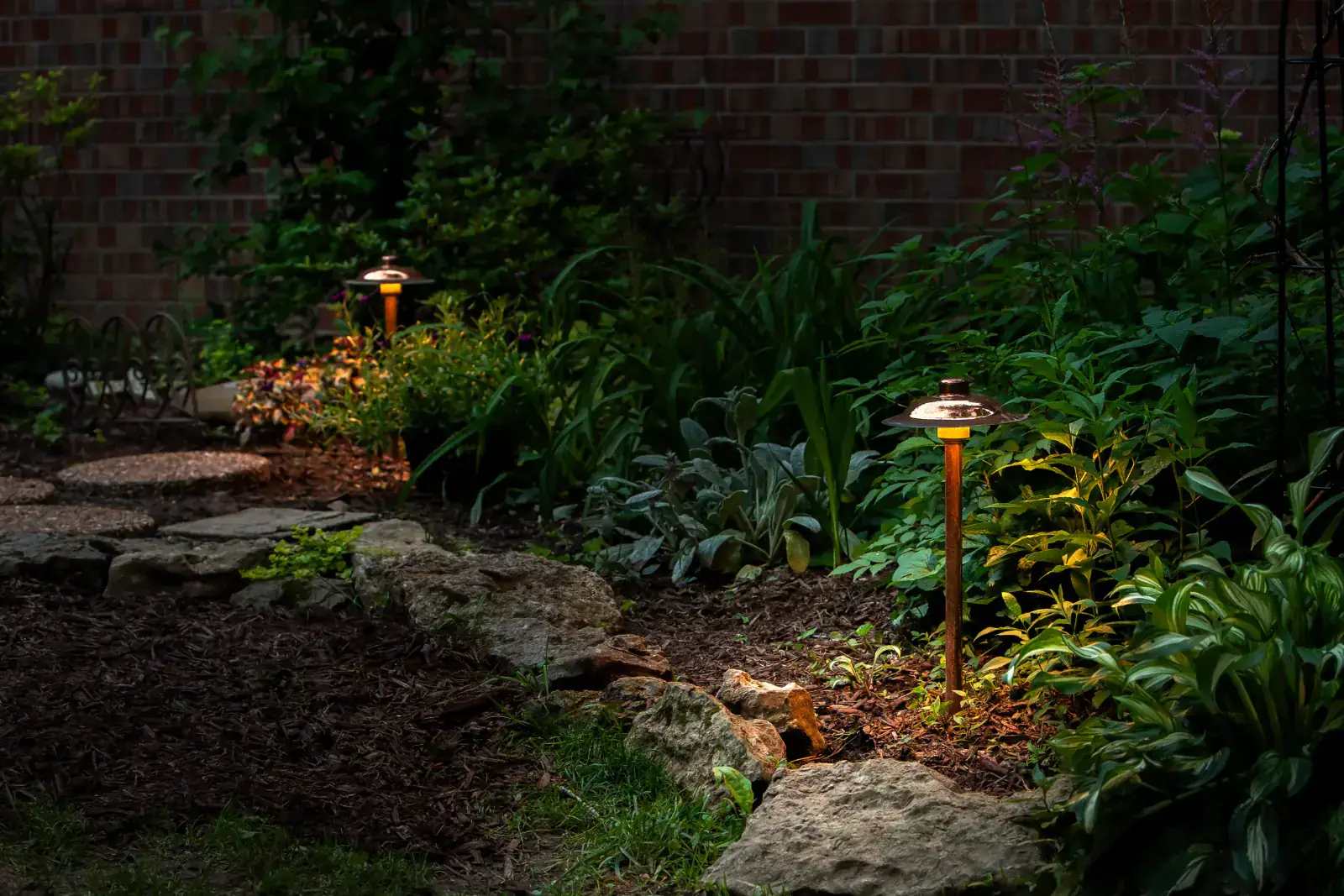 Copper mushroom path lights illuminating a stone garden path bordered by lush perennials at night, Nashville, TN