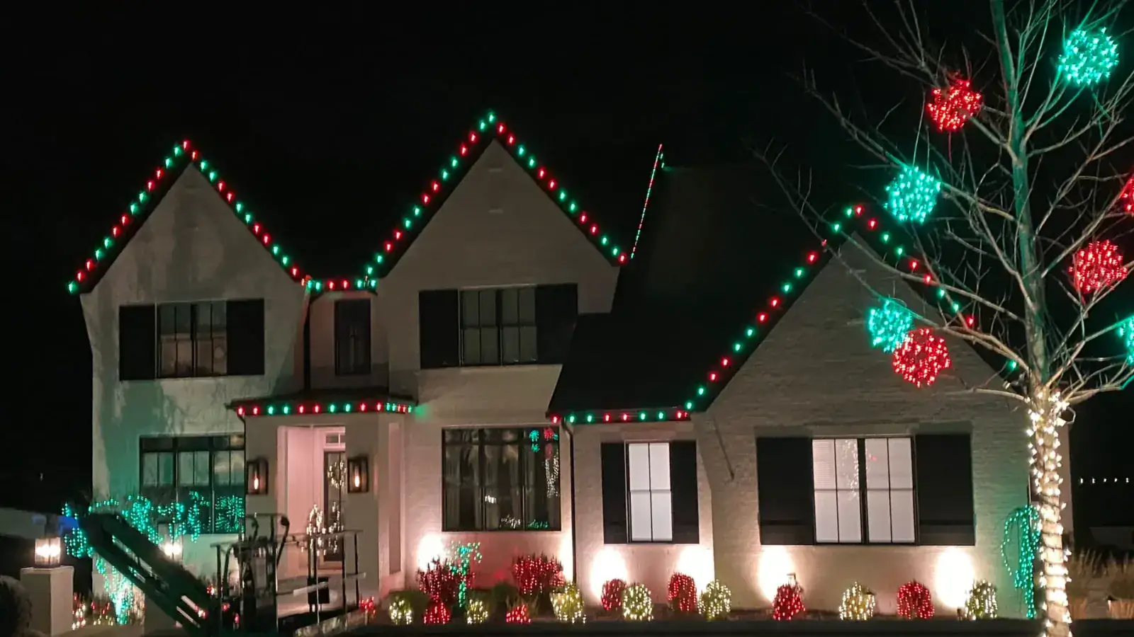 A home decorated with red and green programmable roofline lighting at night