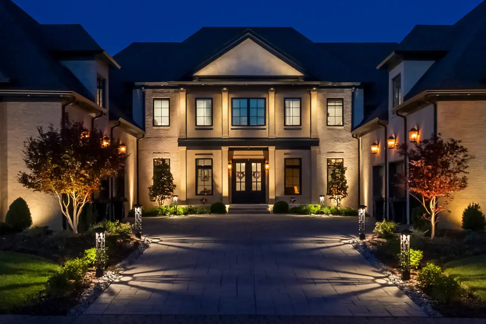 Real photo of a luxury home facade with landscape and architectural lighting at night by Light TN