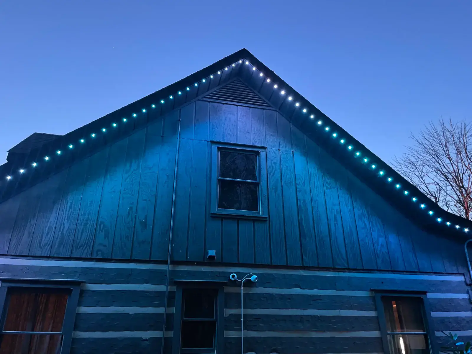 A barn with teal programmable roofline LED lighting glowing along the eaves at dusk