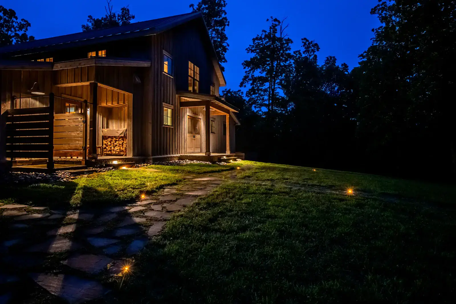 Rustic board-and-batten barn-style home with warm LED step lighting, in-ground path lights on flagstone, and blue-hour sky, Middle Tennessee