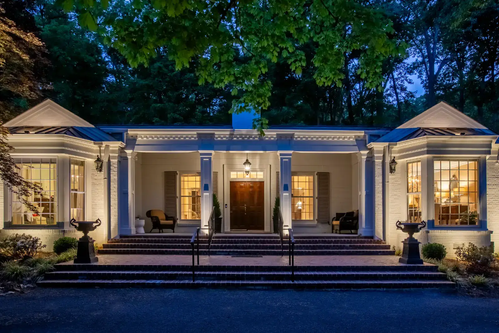 A Nashville historic estate with architectural lighting at blue hour, columns and steps illuminated