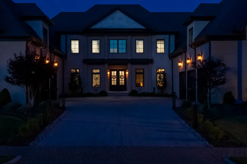 A Belle Meade estate facade at dusk, symmetrical two-story home with warm lantern lighting