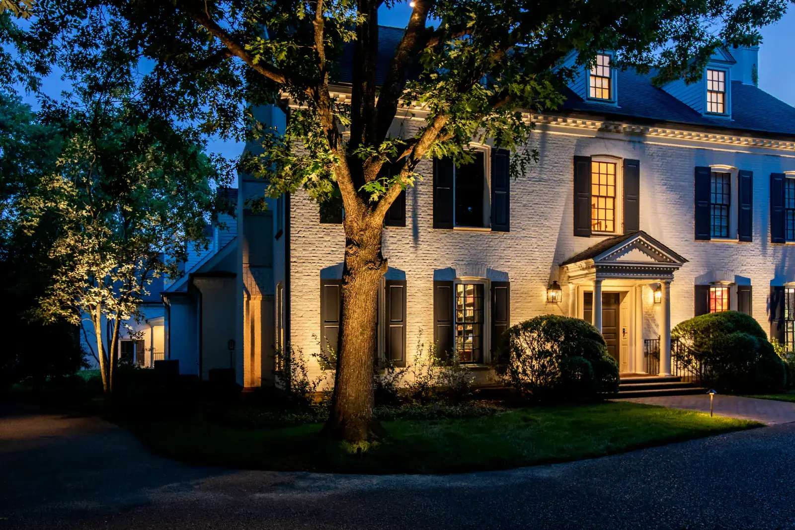 A Green Hills Georgian home lit after dark with tree uplighting and architectural facade lighting