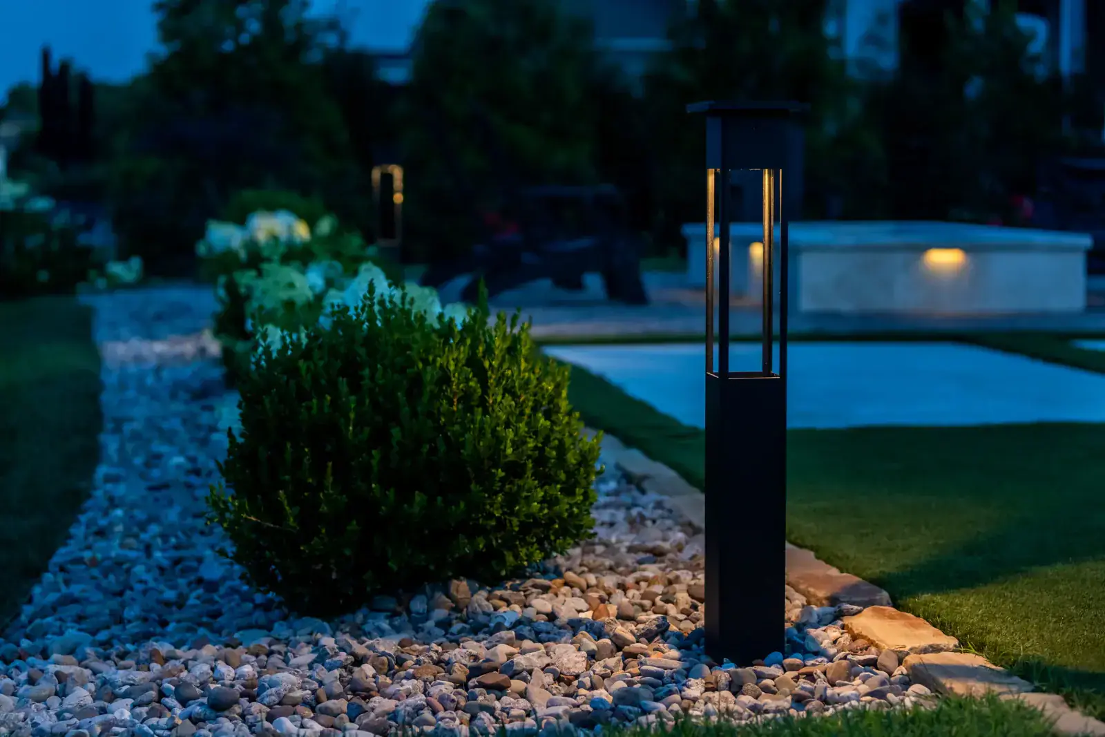 Bollard and path lighting along a garden bed at dusk