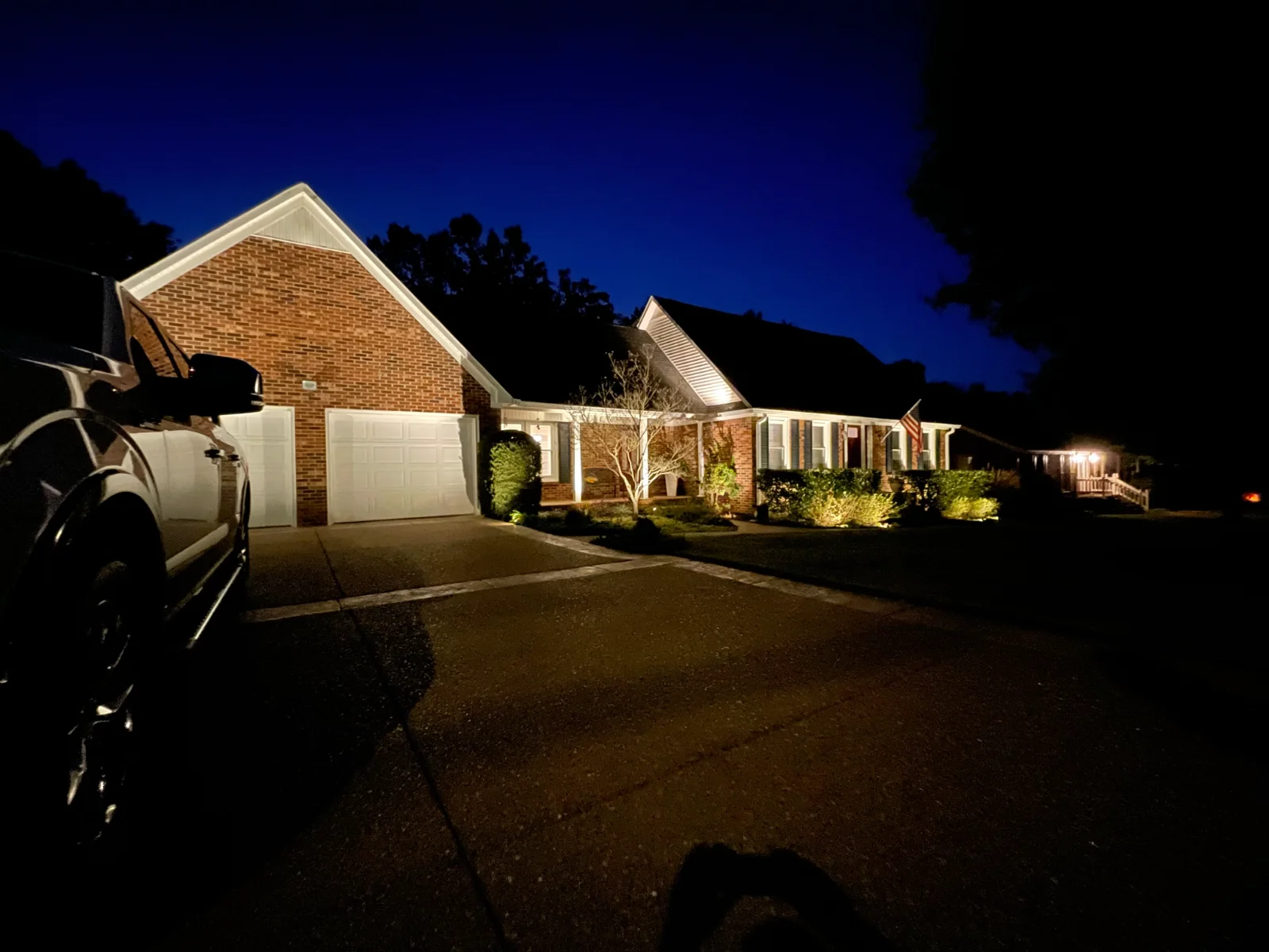 Warm landscape and architectural up-lighting on a brick ranch home at night, Mount Juliet TN